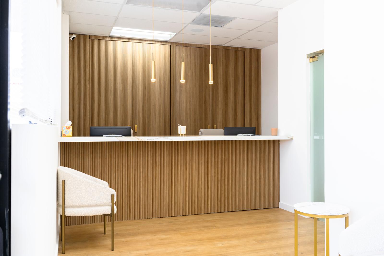 Royalty Dental reception desk with wood paneling and gold pendant lights